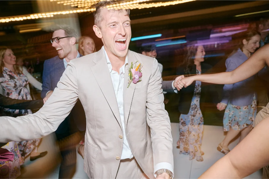 A motion-lights shot of a groom laughing and dancing in the center of the dance floor.