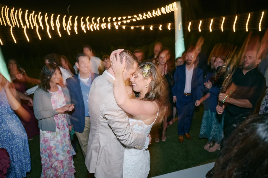 Bride and groom holding eachother and dancing on a high energy dance floor, surrounded by family and friends.